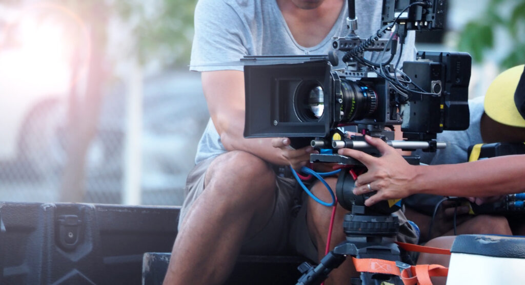 Blurry image of behind the scenes. Film Production crew team setting camera for shooting movie or online video. Outdoor shooting with professional camera.